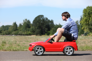 Man sitting on a small red car